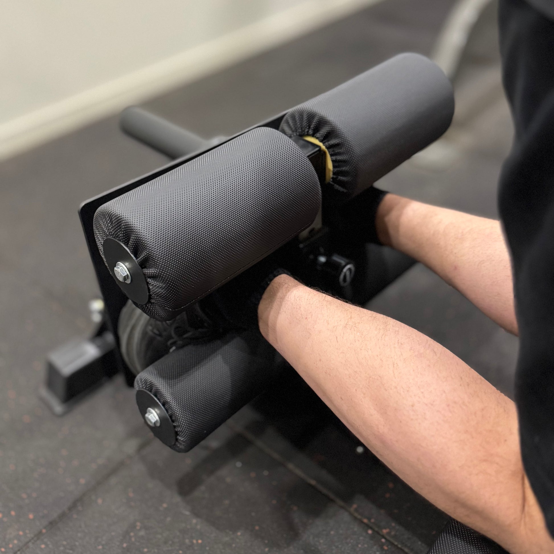 Person using a black exercise machine on a gray floor.