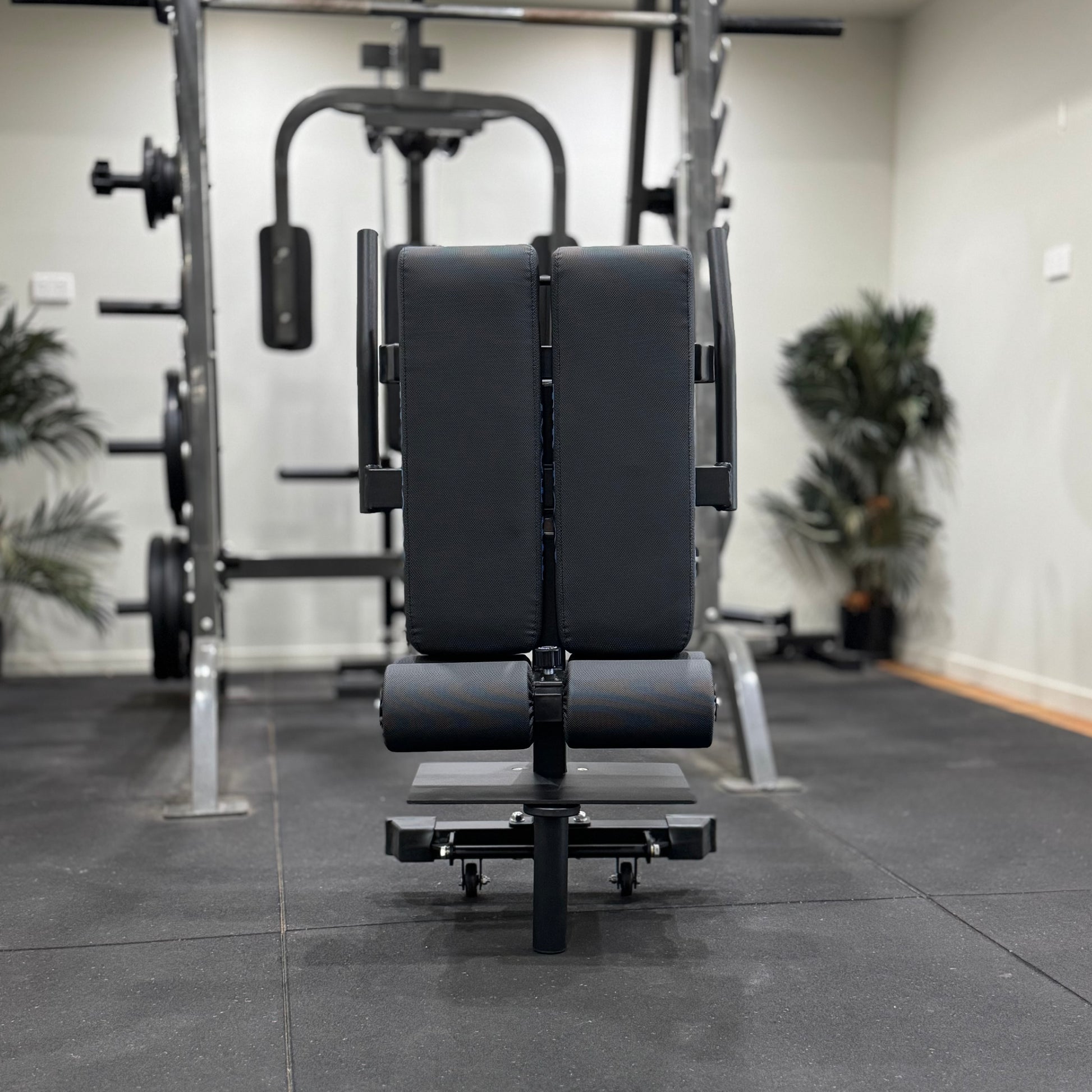 Black weight bench in a gym setting with exercise equipment in the background