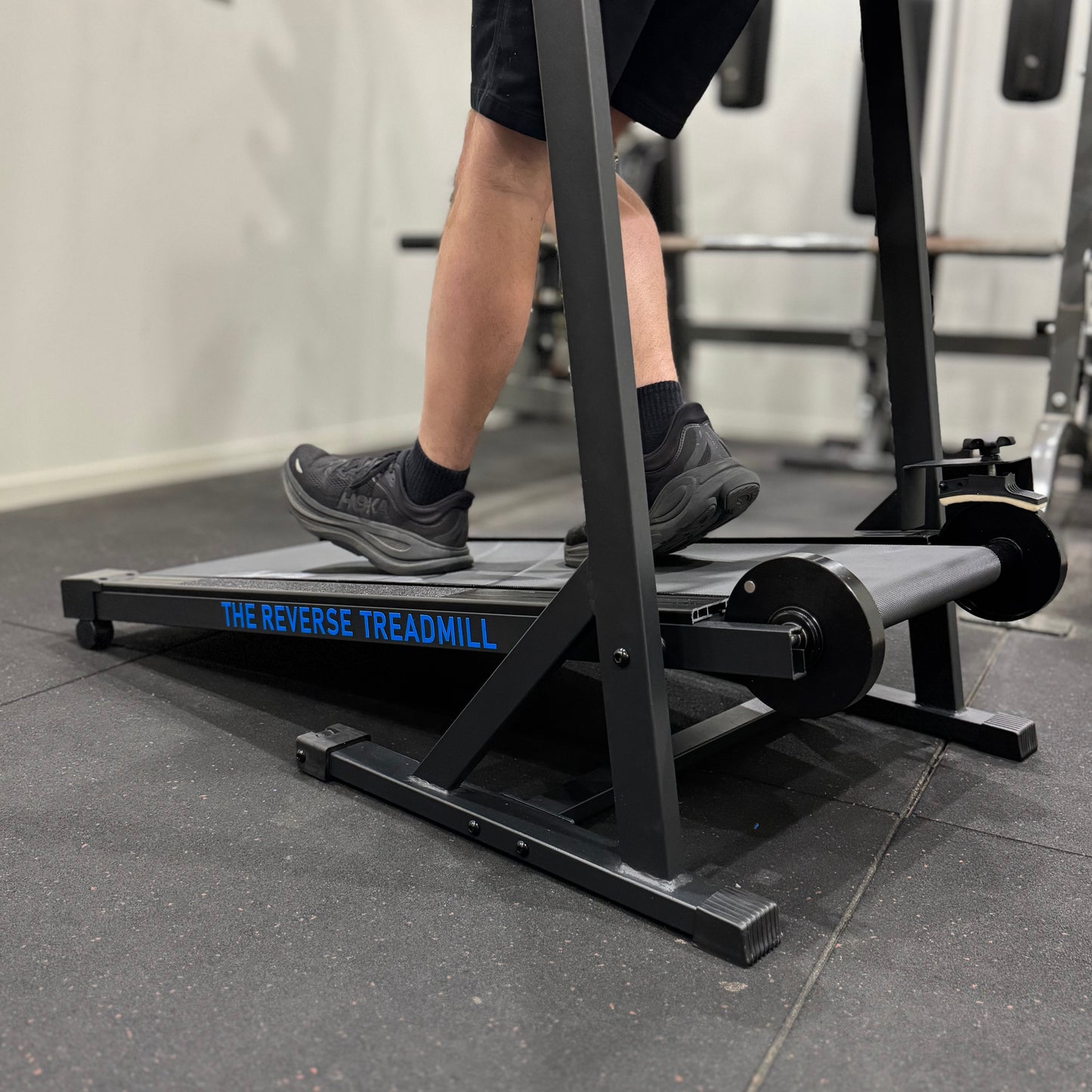 Person using a reverse treadmill in a gym setting