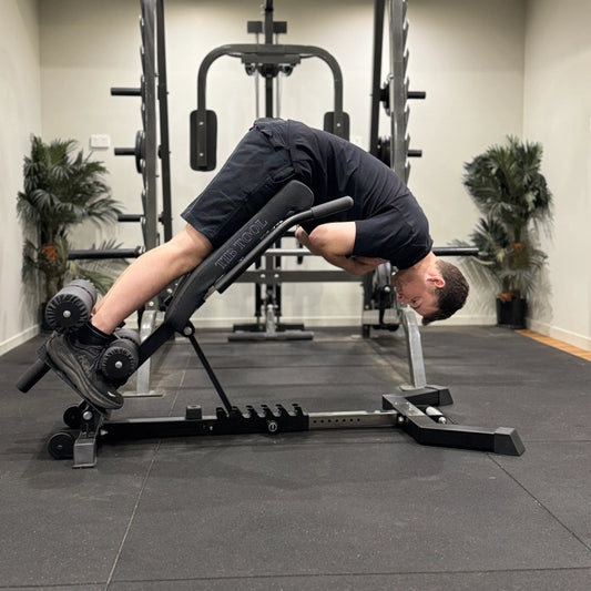 Person using a Nordic back extension weight bench in a gym setting.