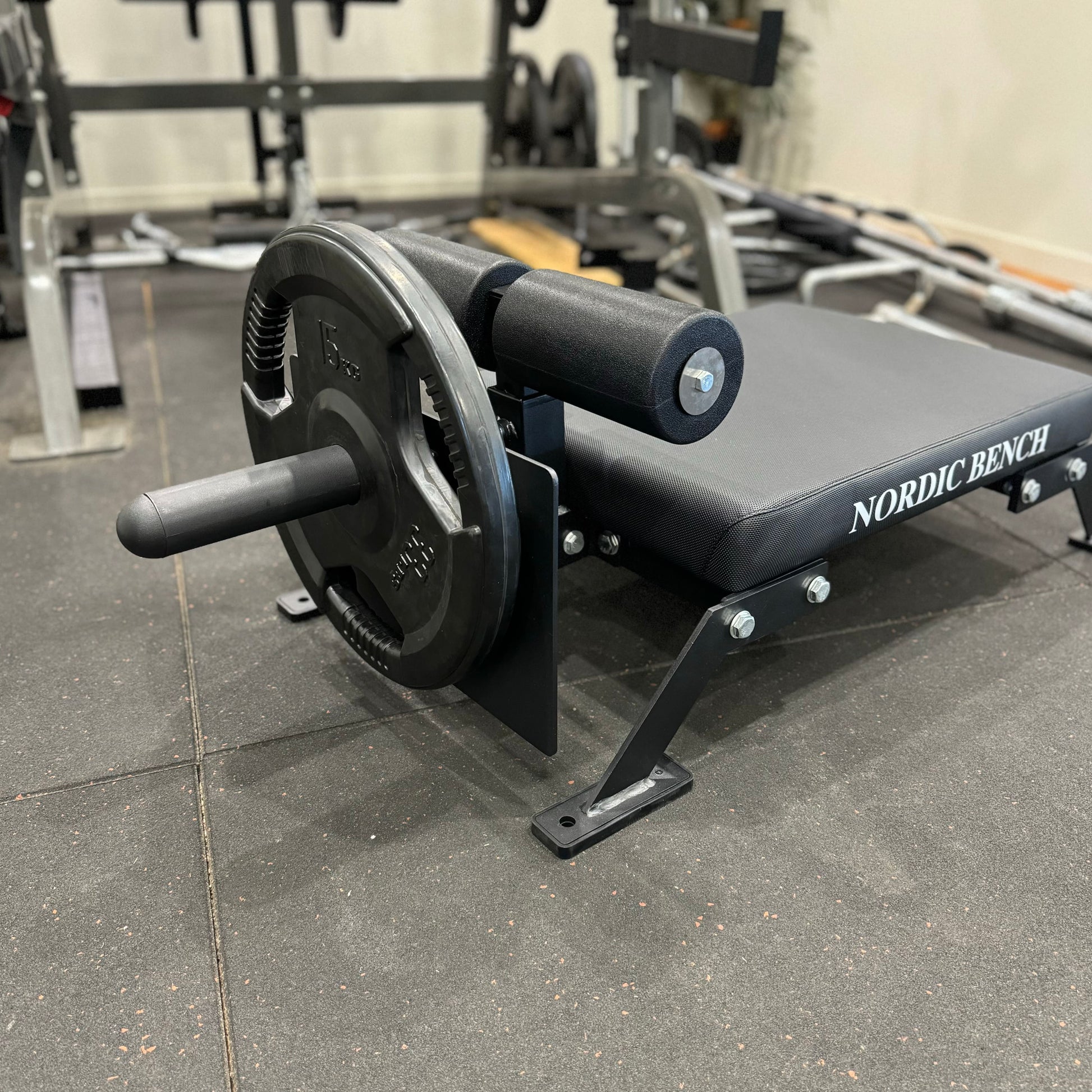 A close-up of a Nordic Bar bench with weights, showcasing the sturdy design and gym setting.