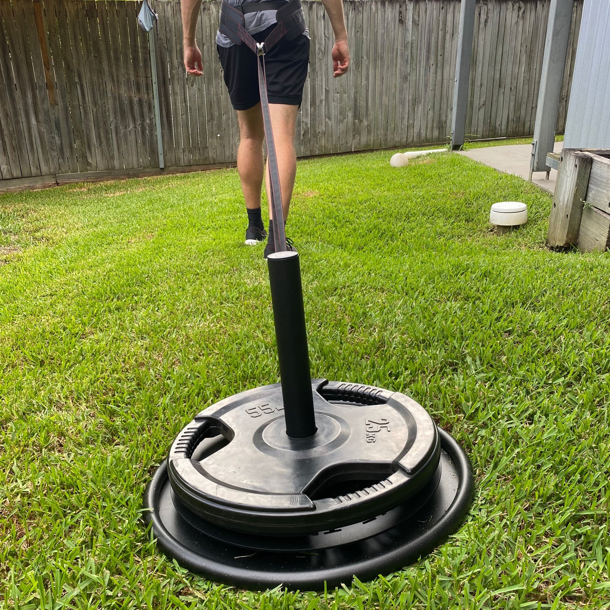A person training outdoors with a sled on grass, focusing on strength and fitness activities. Fitness training and outdoor exercise illustrated.