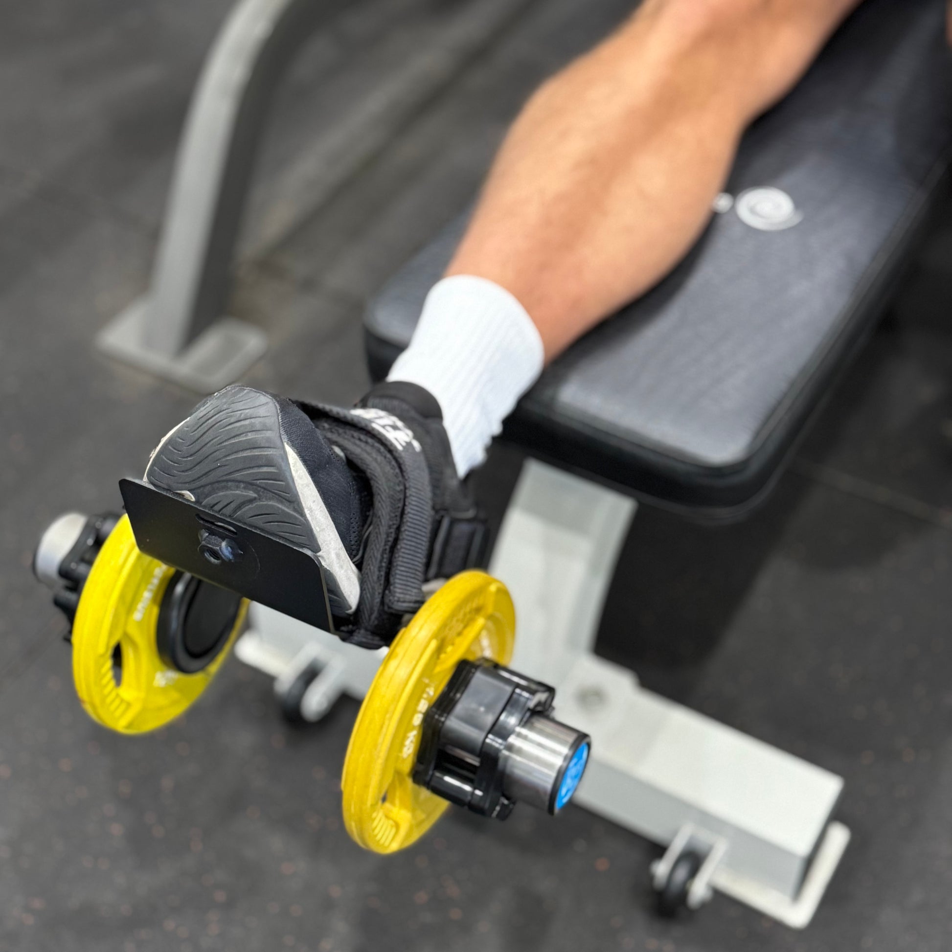 Person using foot attachment to lift weights for hamstrings and ankles.
