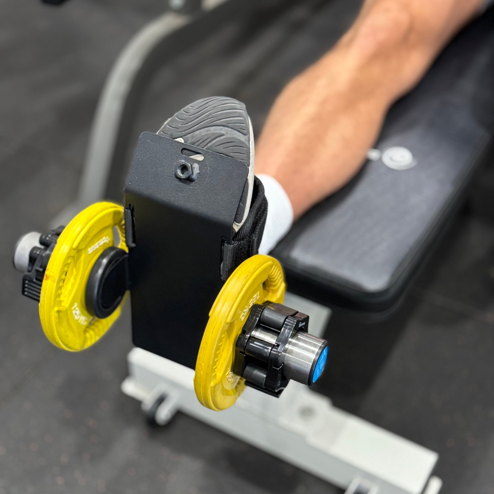Person using weights attached to foot to train ankle mobility.