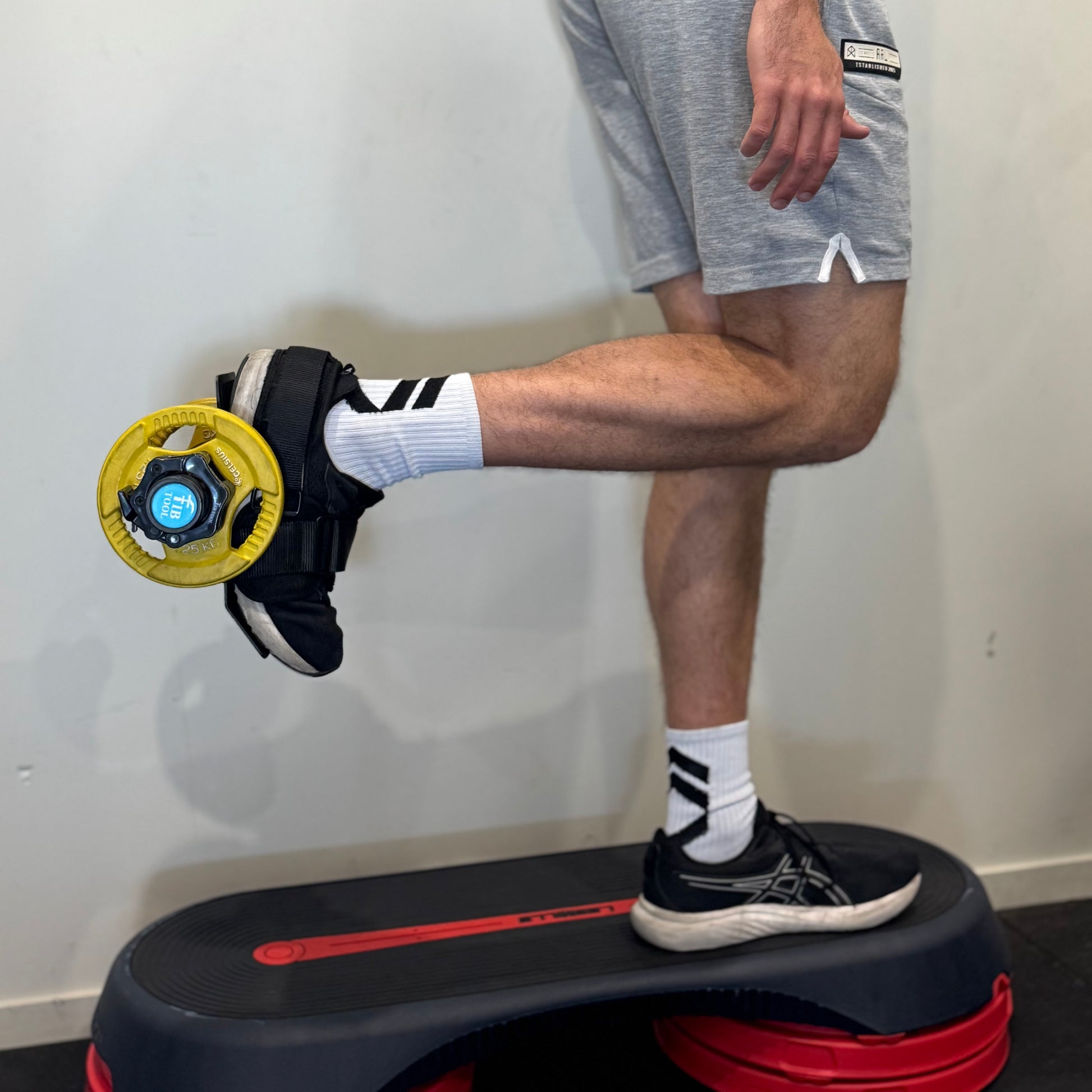 Person using a tib bar ankle weight attachment for hamstrings.
