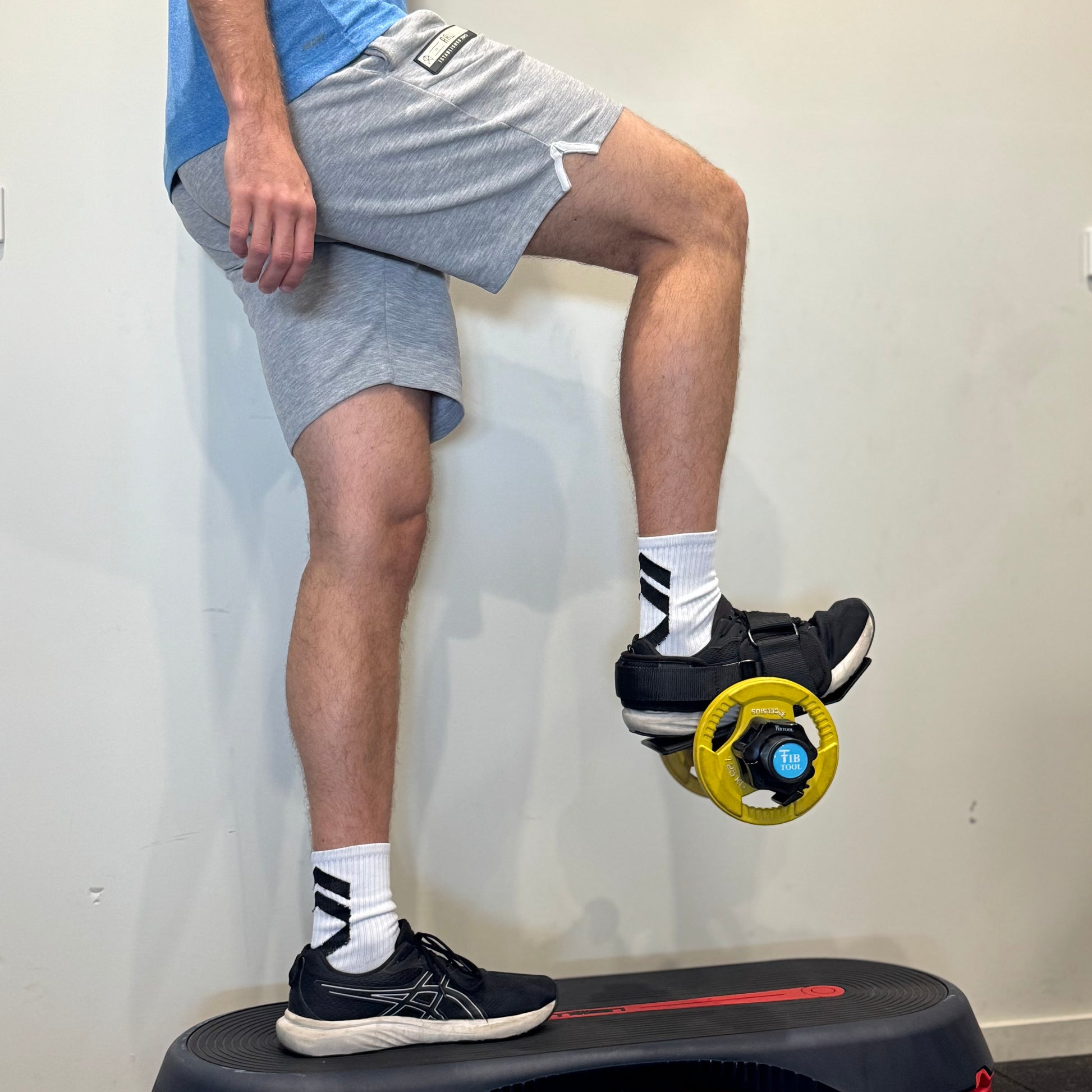 Person using tib bar ankle weight attachment for hip flexors