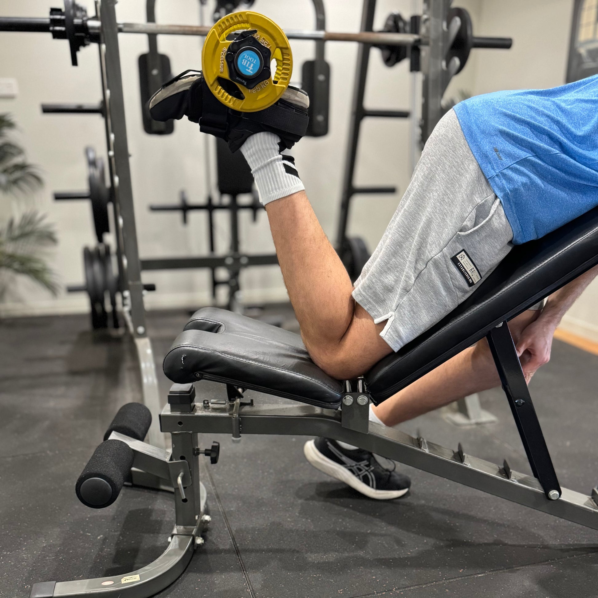 Person using ankle weight attachment tib bar to train hamstring strength.