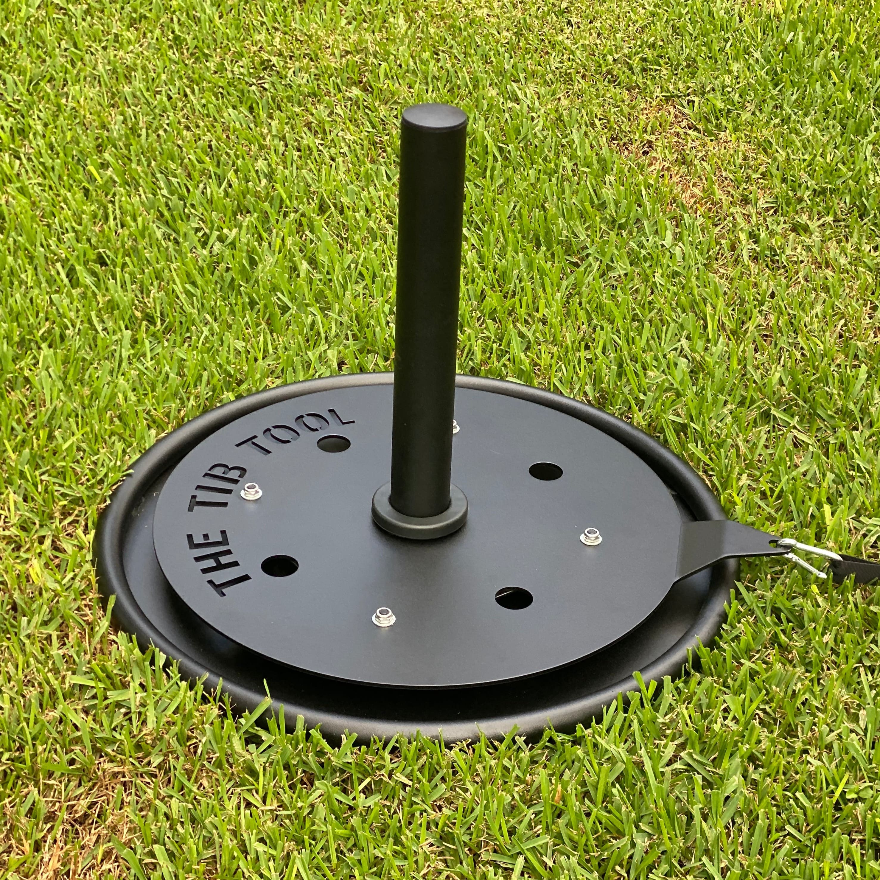 A close-up view of the TTB Tool, a unique gardening device designed for efficient planting and outdoor projects, resting on a lush green lawn.