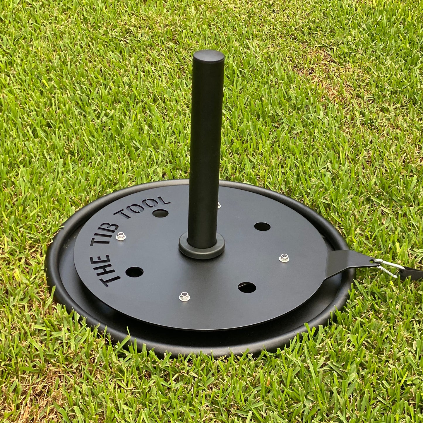 A close-up view of the TTB Tool, a unique gardening device designed for efficient planting and outdoor projects, resting on a lush green lawn.