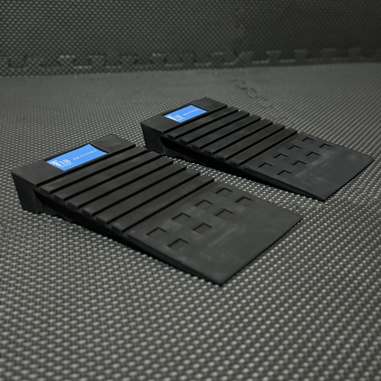 Two black squat wedges designed for gym use, positioned on a textured mat, enhancing workout performance.