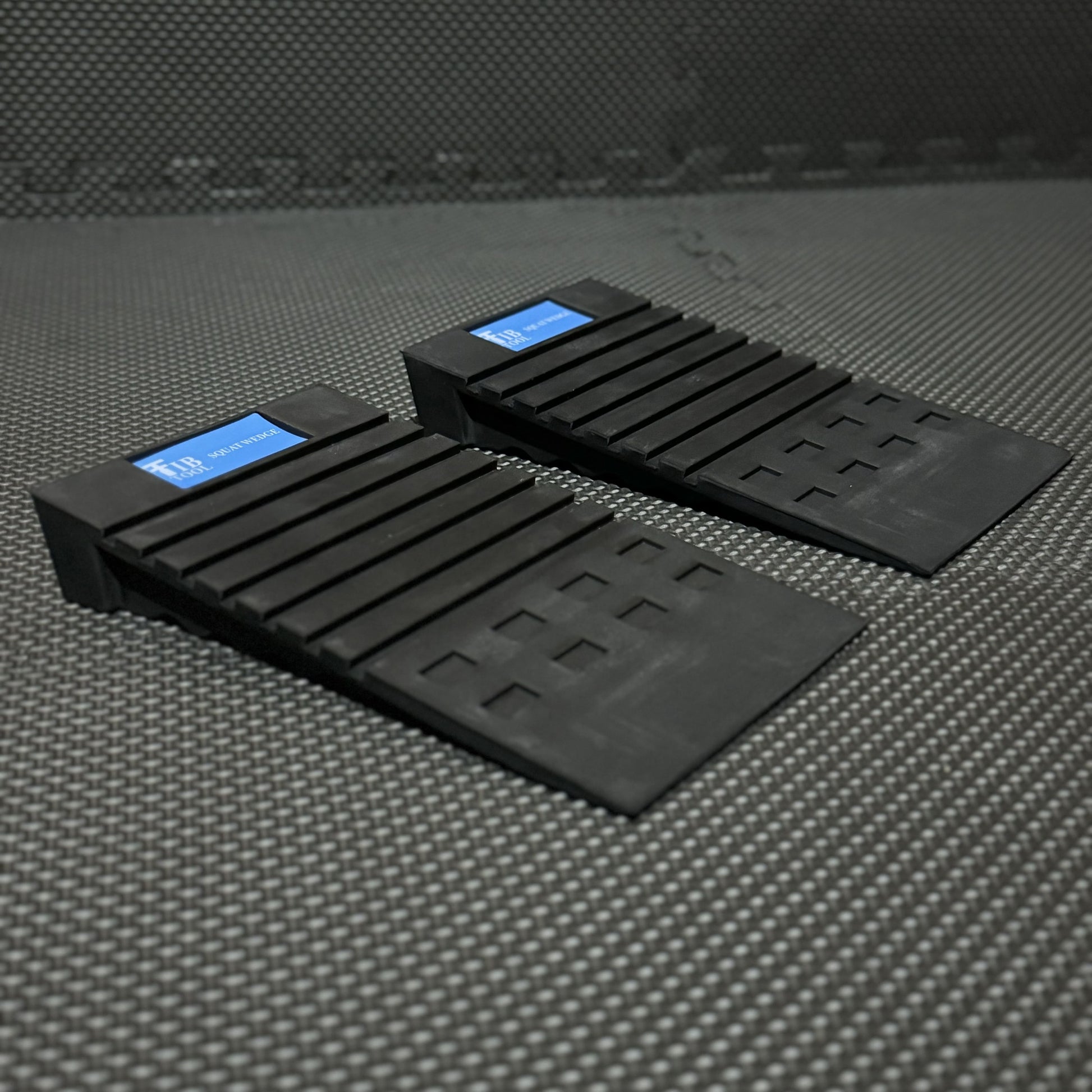 Two black squat wedges designed for gym use, positioned on a textured mat, enhancing workout performance.