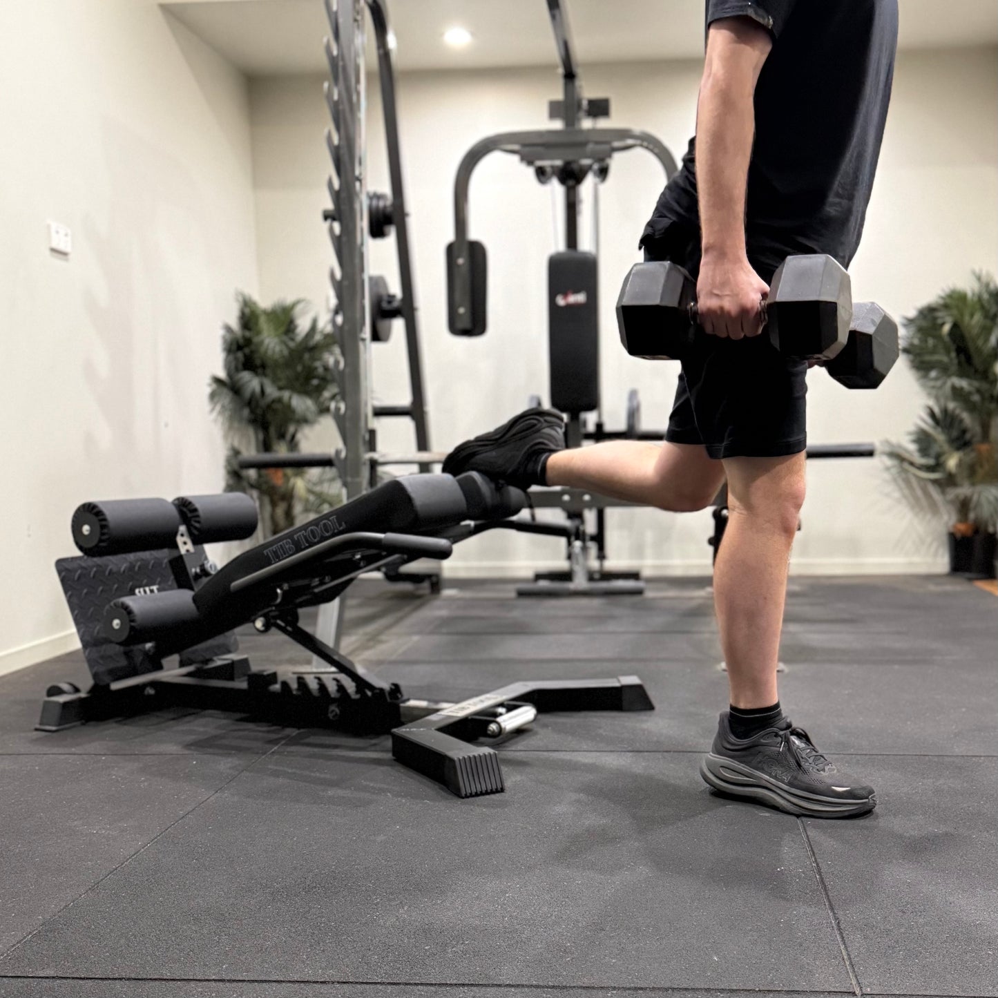 Person doing split squats with dumbbells in a gym setting.