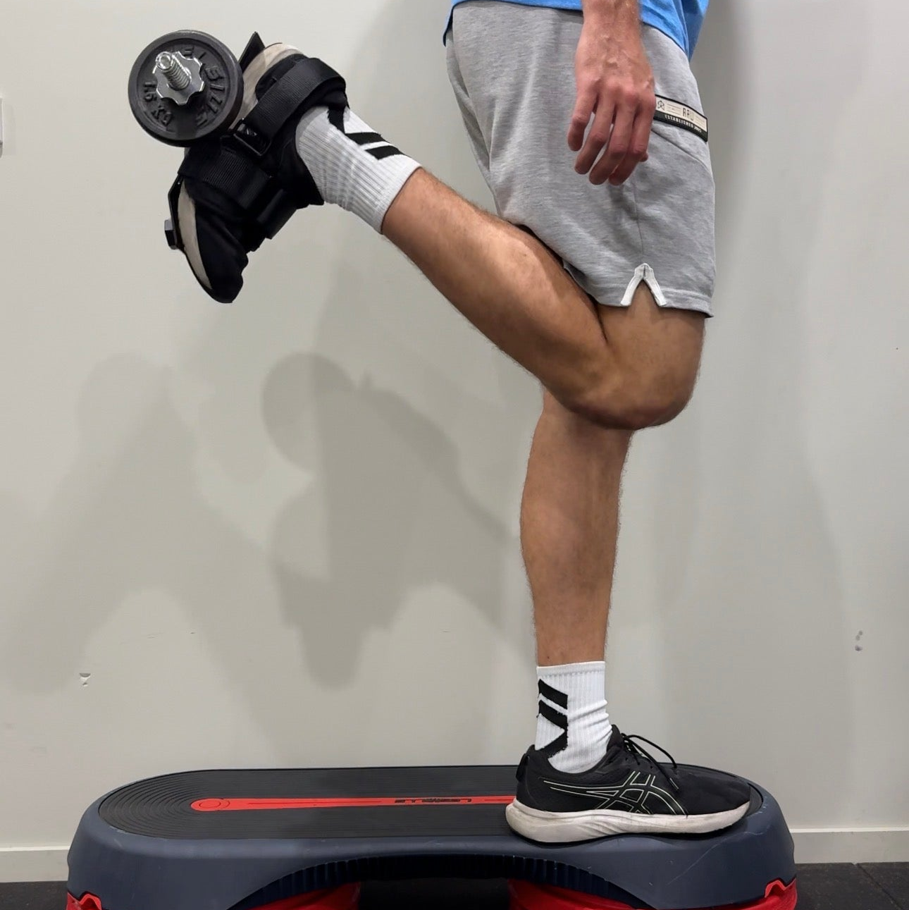 Person using a step platform to perform hamstring curls.