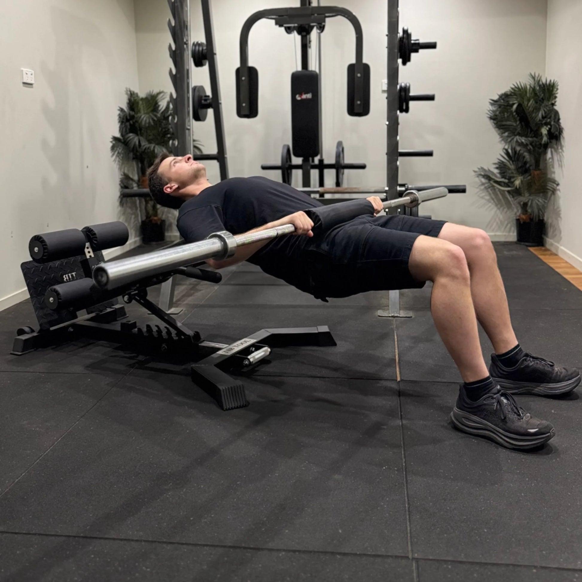 Person performing hip thrusts with a barbell in a gym setting. 