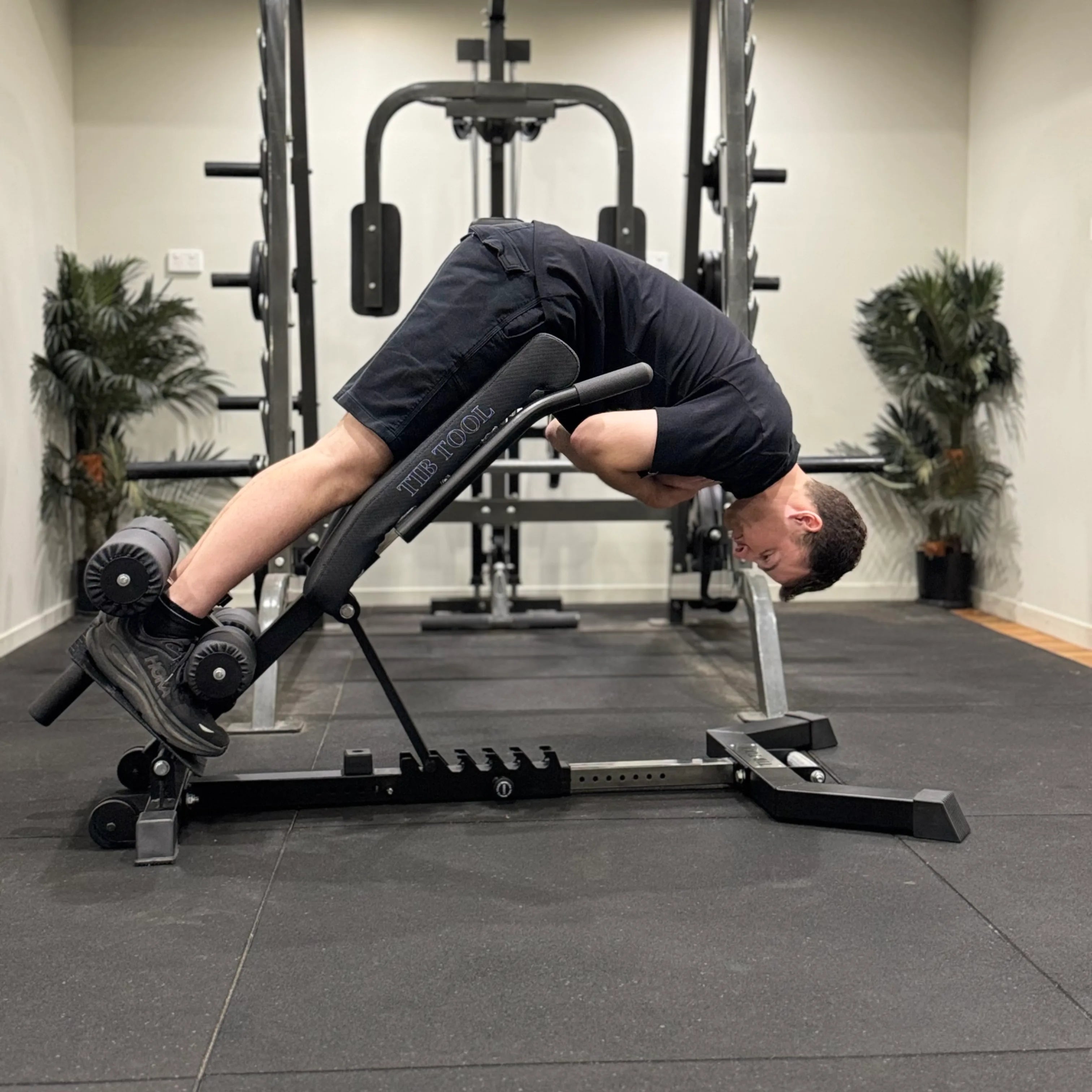 Person using a Nordic back extension weight bench in a gym setting.