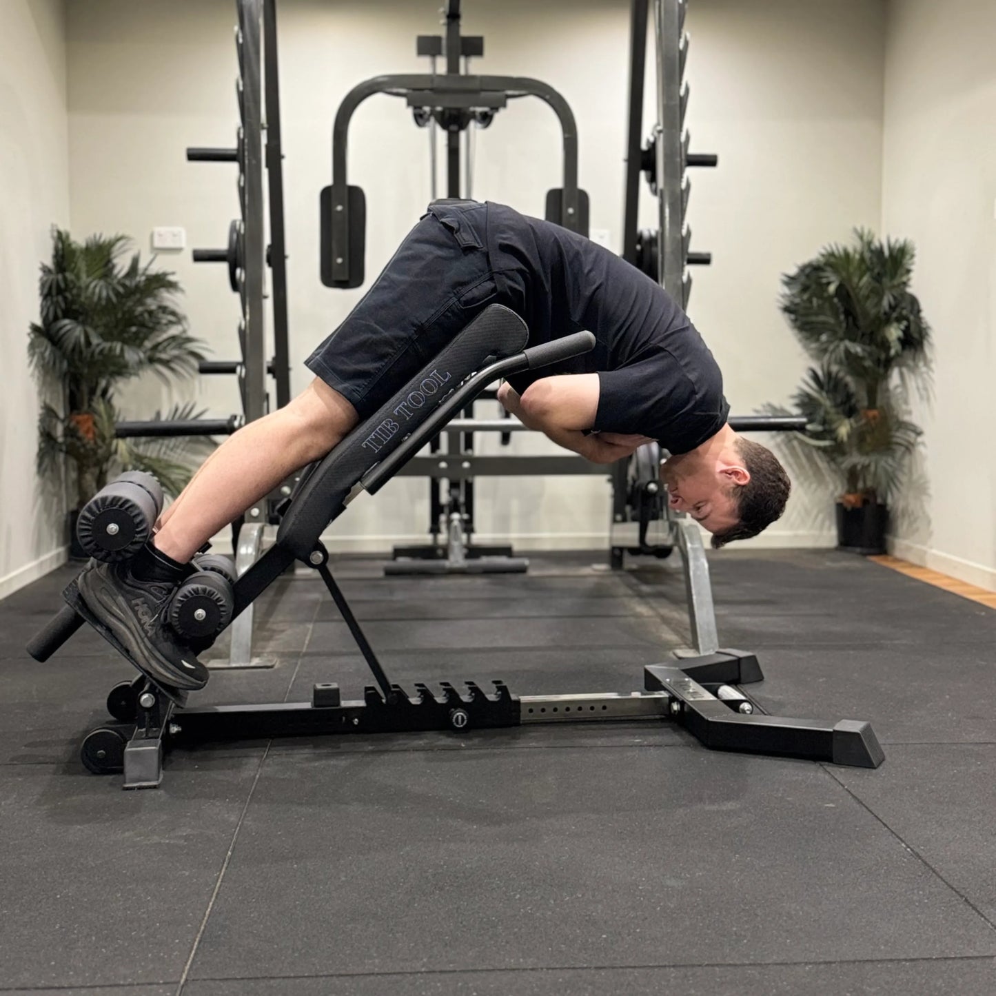 Person using a Nordic back extension weight bench in a gym setting.