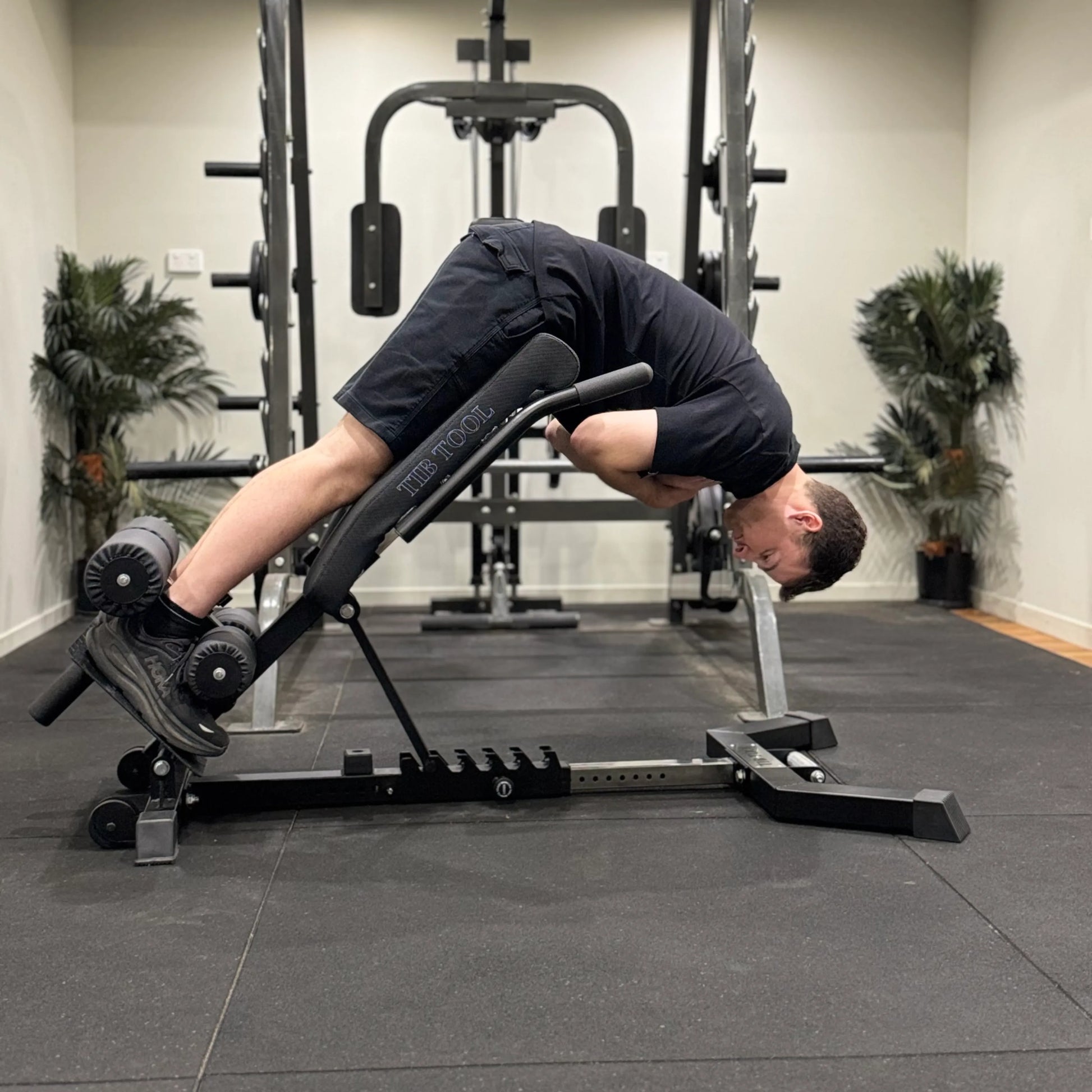 Person using a Nordic back extension weight bench in a gym setting.